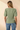 Back view of model wearing sage green ribbed knit top with blue jeans