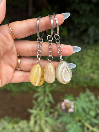Yellow Botswana Agate Crystal Keychain featuring polished yellow-green patterned gemstones held outdoors