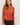Front view of model wearing orange button-up cardigan with black pants
