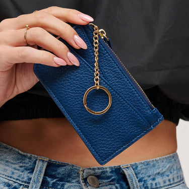 Adriana Card Holder Navy held in a woman's hand with a gold keychain detail, showcasing its chic design.