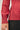 Close-up view of model wearing red raglan sleeve pullover sweater with black pants