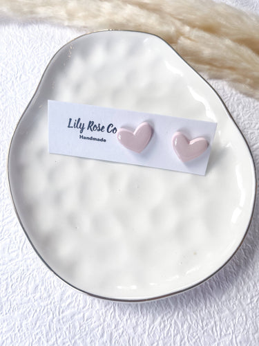 Hearts and Valentine’s Stud Earrings on a decorative plate by Lily Rose Co, showcasing handcrafted pink heart designs.