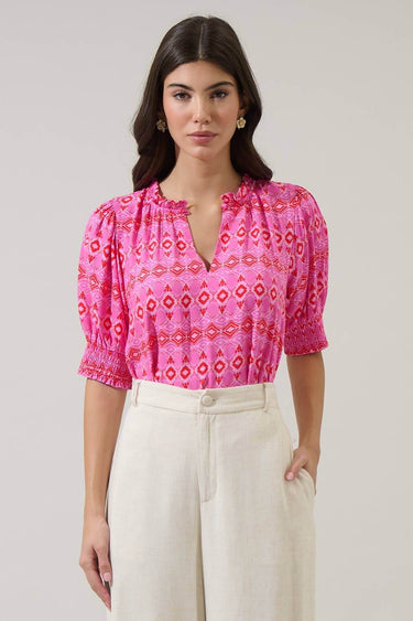 Model wearing Mirany Ikat Bindy Puff Sleeve Top with pink ikat print and puff sleeves, styled with high-waisted trousers.