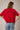 Back view of model wearing red short sleeve sweater cardigan with jeans