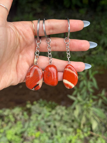 Red Jasper Crystal Keychain featuring polished reddish-orange gemstones displayed in a hand outdoors