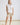 White collared V neck button down line lace detail shirt with beige shorts, full-length view
