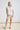 White collared V neck button down line lace detail shirt with beige shorts, full-length view
