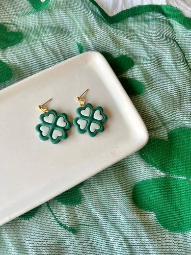 Two Tone Shamrock Earrings Clover Clay Earrings displayed on a plate with a green shamrock background.