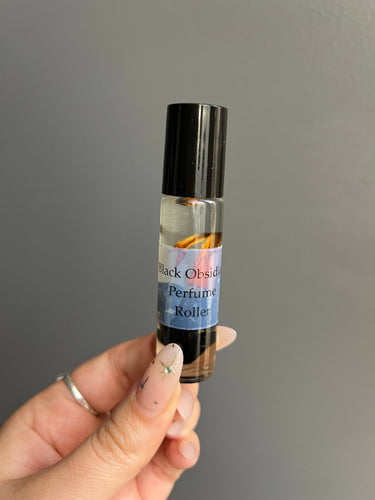 Black Obsidian Crystal Perfume Roller held in hand, showcasing the bottle and label.