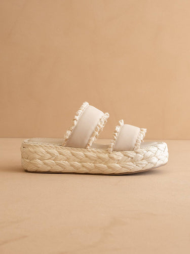 The Polly Cream Ruffle Strap Raffia Platform Slide Sandal featuring double ruffle-trim straps and a braided raffia sole.