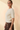 Side view of model wearing cream ribbed knit top with brown pants