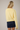 Back view of model wearing yellow Round Rolled Hemline Detail Thin Sweater Cardigan with navy shorts