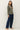 Side view of model wearing sage green raglan sleeve pullover sweater with jeans