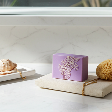 Organic Love Purple Handmade Soap resting on a beige cloth, surrounded by a sea sponge and seashell, with natural light.