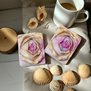 Two Purple Rose Gold Handmade Soap bars with rose design, shells, and a cup of coffee on a cozy blanket.