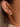 Close-up of Lush 18K Gold Non-Tarnish CZ Pave Huggie Earrings worn on ear, showcasing cubic zirconia detail.