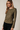 Side view of model wearing olive green Boat Neck Semi Bell Long Sleeve Knit Top with black pants