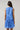 Model wearing the Kaidy Tropical Loly Trapeze Mini Dress in blue, showing the back and ruffle detail.
