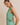 Model wearing BOAT NECK SLEEVELESS SIDE TIES MINI DRESS in green and white stripes,side view