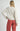 Back view of model wearing Irisha Diamond Pointelle Sweater in Oatmeal, with red pants