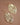 Gold Plated Metal Leaf Drop Earrings 7418 displayed as a pair on a brown background