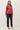 Model wearing red raglan sleeve slub pullover sweater with black pants, full length view