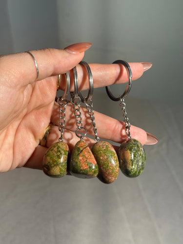 Unakite Crystal Keychain featuring polished green and peach-colored gemstones displayed in a hand