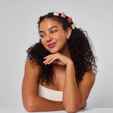 Model showcasing Recycled Mini Cloud Clips 8pc Set - Assorted Cherry Blossom in styled curly hair.