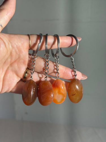 Carnelian Crystal Keychain featuring polished orange and reddish-brown gemstones displayed in a hand