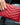 Mackenzie Wallet red in a chevron-quilted design, held in hand, showcasing its compact and stylish features.