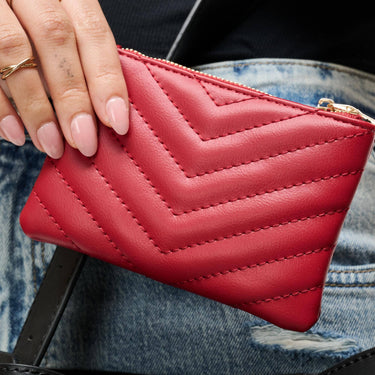 Mackenzie Wallet red in a chevron-quilted design, held in hand, showcasing its compact and stylish features.