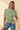 Front view of model wearing sage green ribbed knit top with blue jeans
