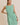 Model wearing a BOAT NECK SLEEVELESS SIDE TIES MINI DRESS in green and white stripes.