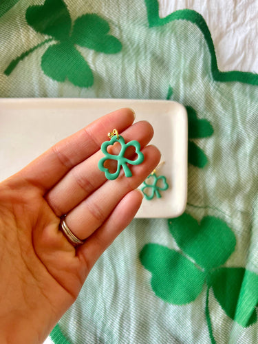 Shamrock Earrings Clover Clay Earrings Clover Earrings held in hand with green clover background.