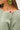 Close-up of sage green slub pullover sweater fabric and neckline detail