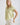 Model wearing a COLLARED V NECK BUTTON DOWN LINE LACE DETAIL SHIRT in light green, paired with white shorts.