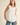 Model wearing a Pleated throughout Sleeveless A Line Top in white with layered pleating details and keyhole back.