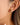 Lush 18K Gold Non-Tarnish CZ Pave Huggie Earrings worn on a model's ear, showcasing the cubic zirconia detail.