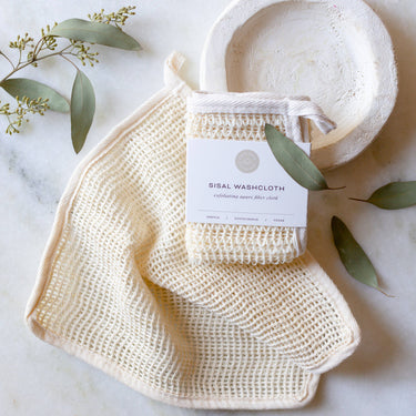Exfoliating Sisal Washcloth Natural Vegan & Eco-Friendly on a marble surface with a decorative bowl.