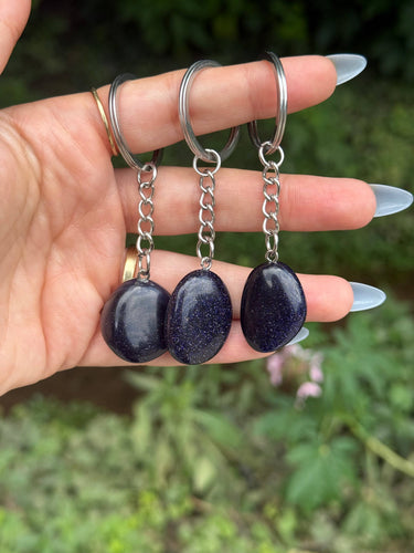 Blue Goldstone Crystal Keychain featuring polished deep blue sparkling gemstones displayed in a hand