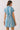 Back view of a woman wearing a Blue Stripe Button Down Shirt Mini Dress with short sleeves and cinched waist.