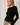 Model wearing black Boat Neck Semi Bell Long Sleeve Knit Top with patterned pants