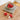 Felt Mushroom Keychain Bag Charm collection displayed in a bowl on a textured mat, showcasing their vibrant colors.