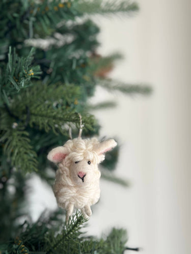 Felt Mini Sheep Keychain hanging on a Christmas tree, hand-made from organic wool and eco-friendly dyes.