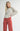 Model wearing Irisha oatmeal diamond pointelle sweater with red pants, arm extended