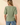 Back view of model wearing sage green ribbed knit top with blue jeans