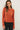 Front view of model wearing orange button-up cardigan with black pants