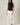 Model wearing HIGH NECK EXTENDED SHOULDER SIDE RUCHED POLKA DOT TOP paired with white wide-leg pants.