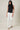Model wearing HIGH NECK EXTENDED SHOULDER SIDE RUCHED POLKA DOT TOP paired with white wide-leg pants.