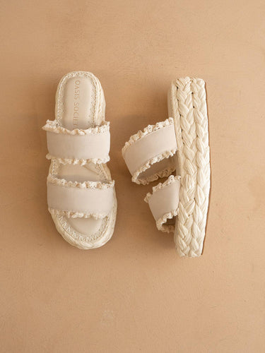 The Polly Cream Ruffle Strap Raffia Platform Slide Sandal with double ruffle straps and braided sole on a neutral surface.